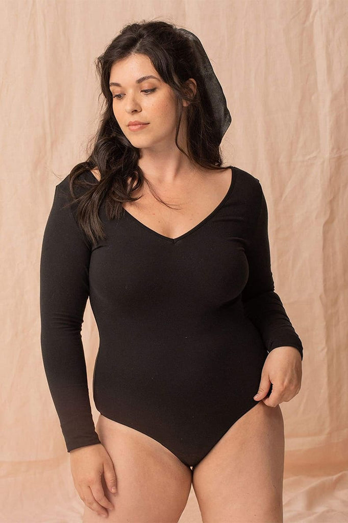 Jeune femme brune debout porte un body Loma noir en Tencel imaginé et confectionné en France par la marque de lingerie éthique Olly.