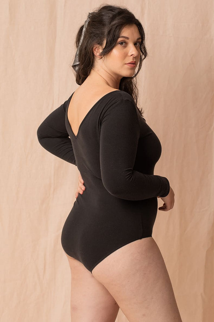 Jeune femme brune debout porte un body Loma noir en Tencel, confectionné en France de la marque écoresponsable Olly lingerie.